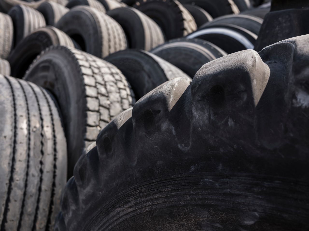Close-up of a pile of used tires in an outdoor industrial setting, highlighting recycling and sustainability.
